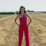 girl in field wearing bright pink jumpsuit