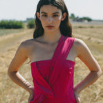 girl in field wearing a bright pink jumpsuit with pleated detail
