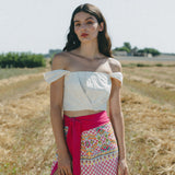girl in field with white crop top and embroidered colourful sarong