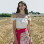 girl in field wearing white crop top and embroidered sarong
