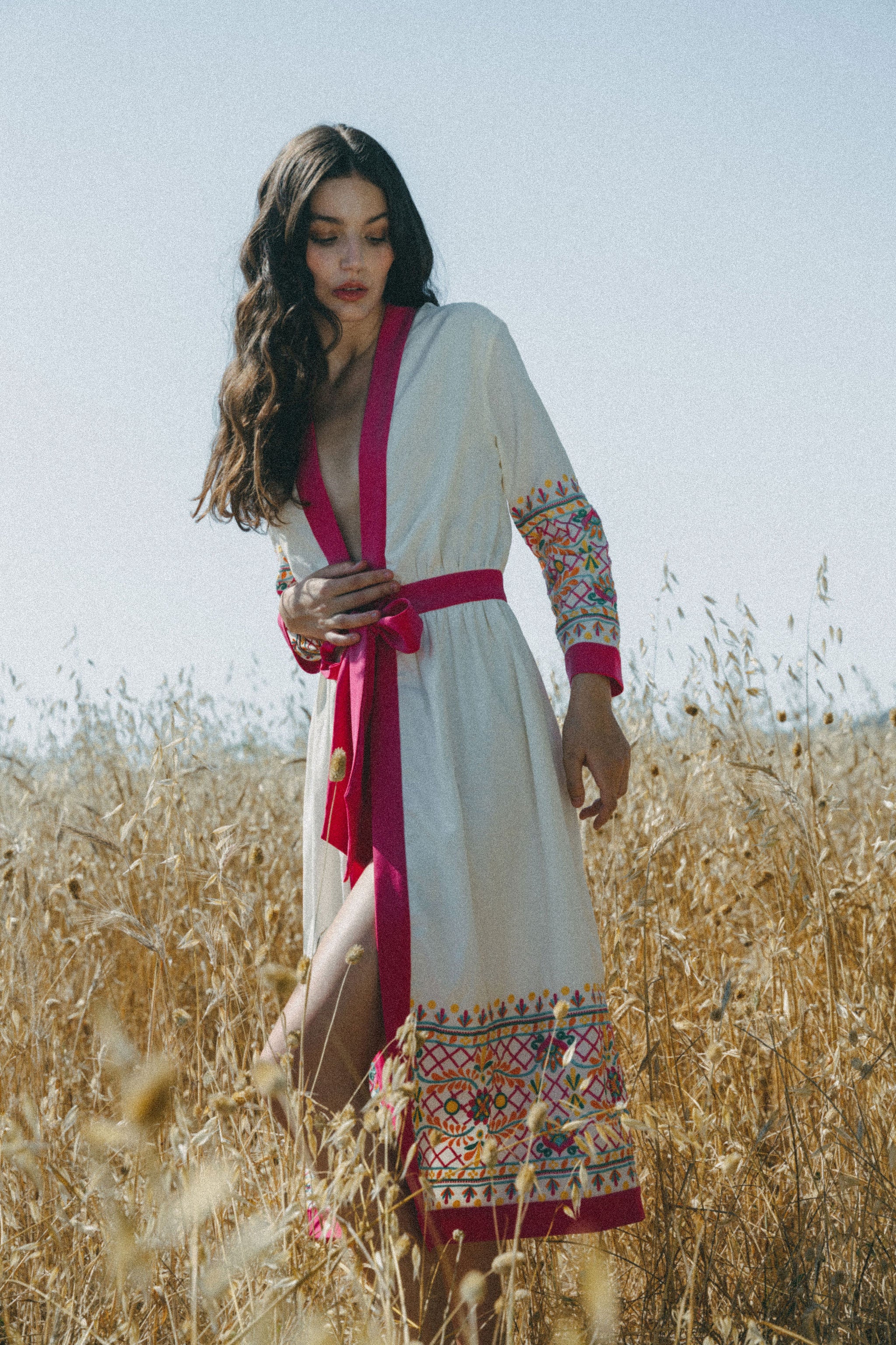girl in field with white embroidered cover up with pink border