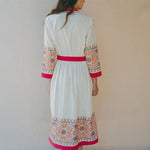 back of cream coverup with embroidery on sleeves and pink border