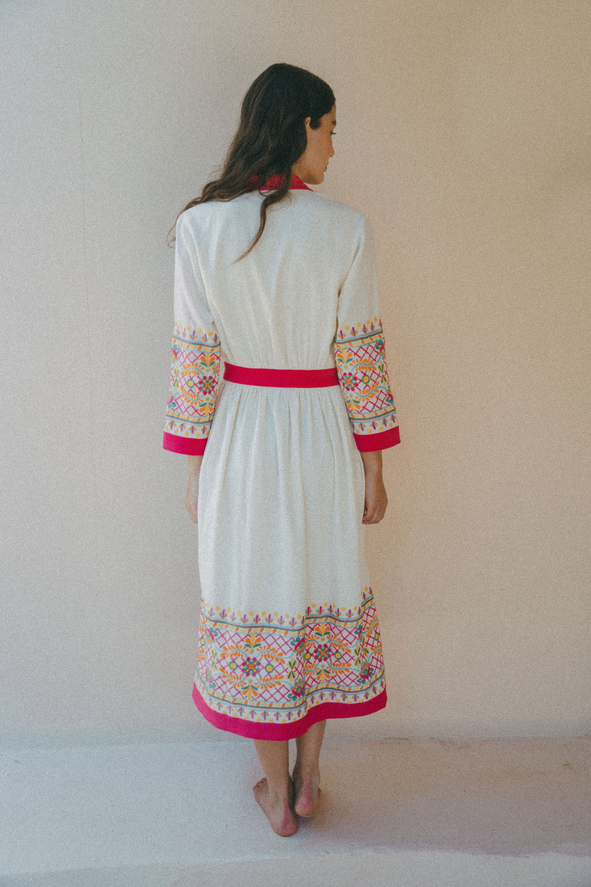 back of cream coverup with embroidery on sleeves and pink border