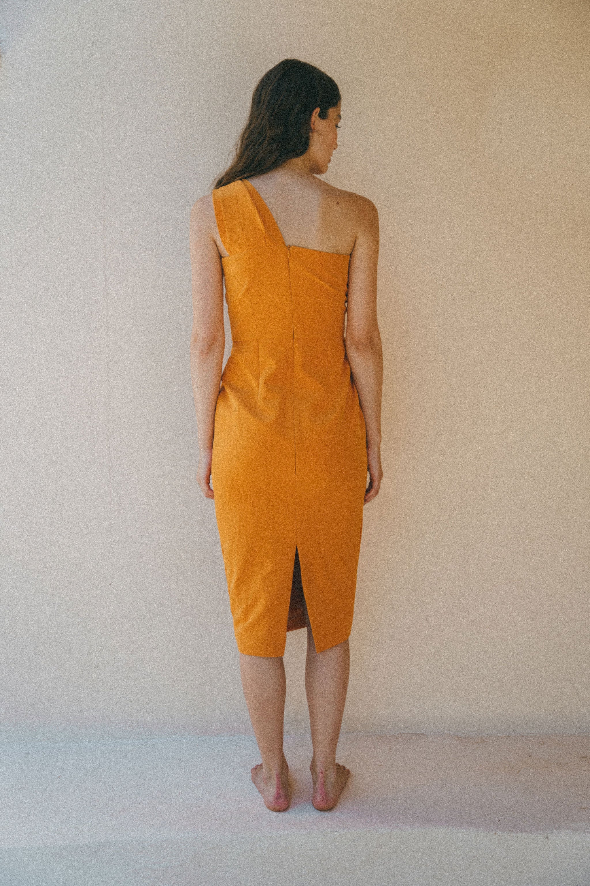 back of orange fitted dress with pleating details