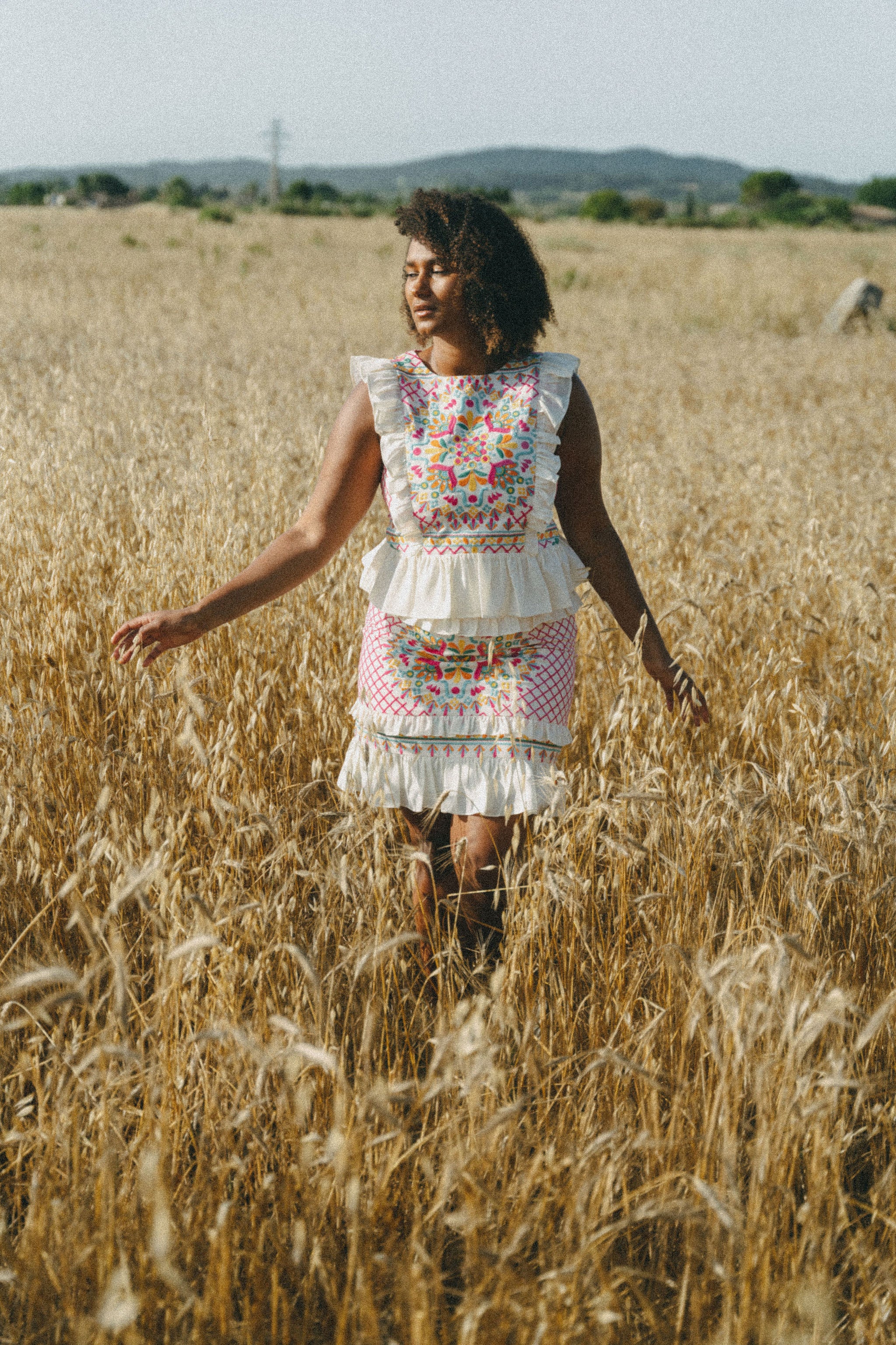 girl in field wearing an embroidered colourful frill top and skirt