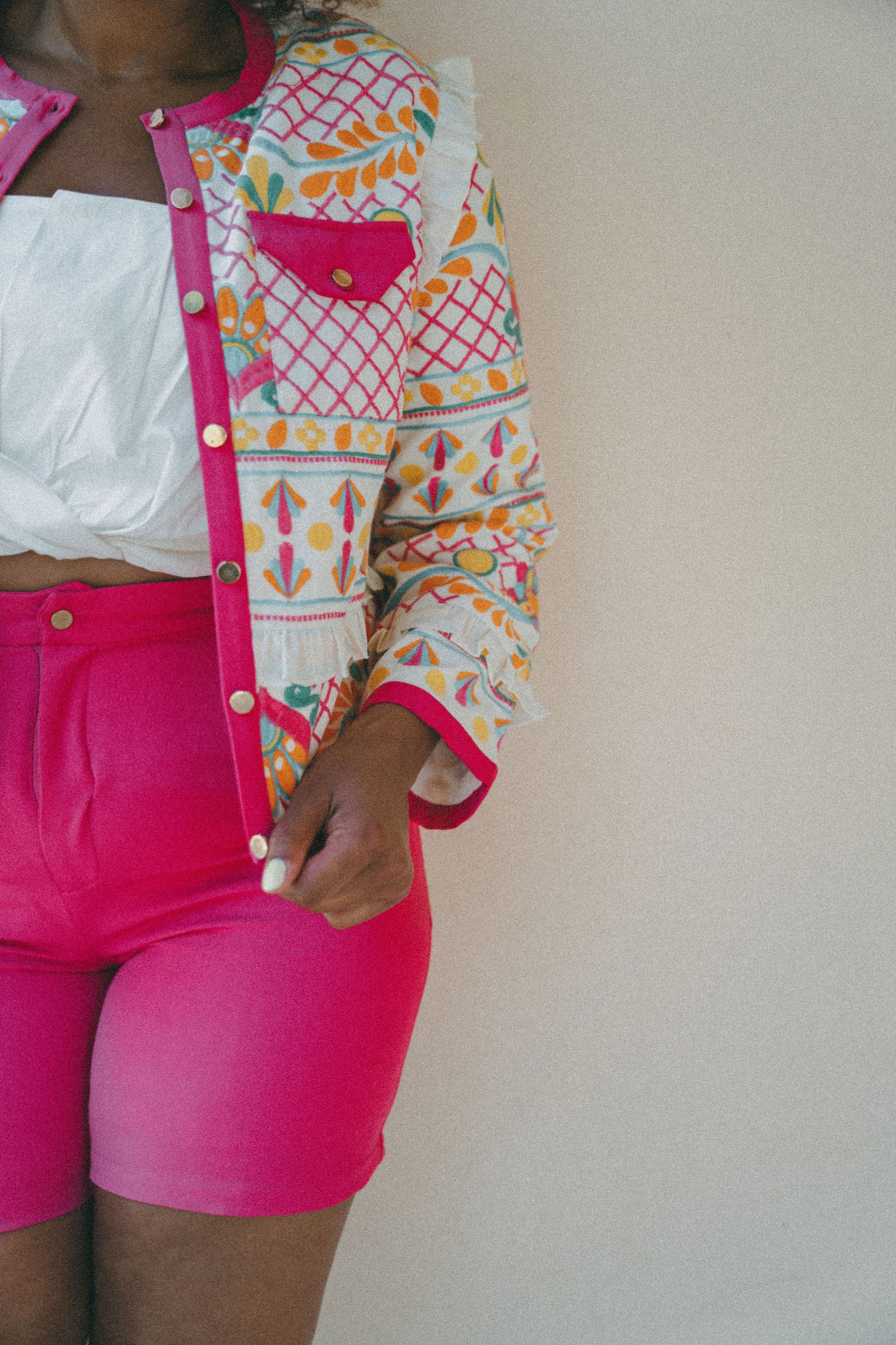 close up of bright pink shorts and embroidered jacket 