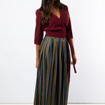 Model wears maroon pleated wrap shirt with printed maxi skirt