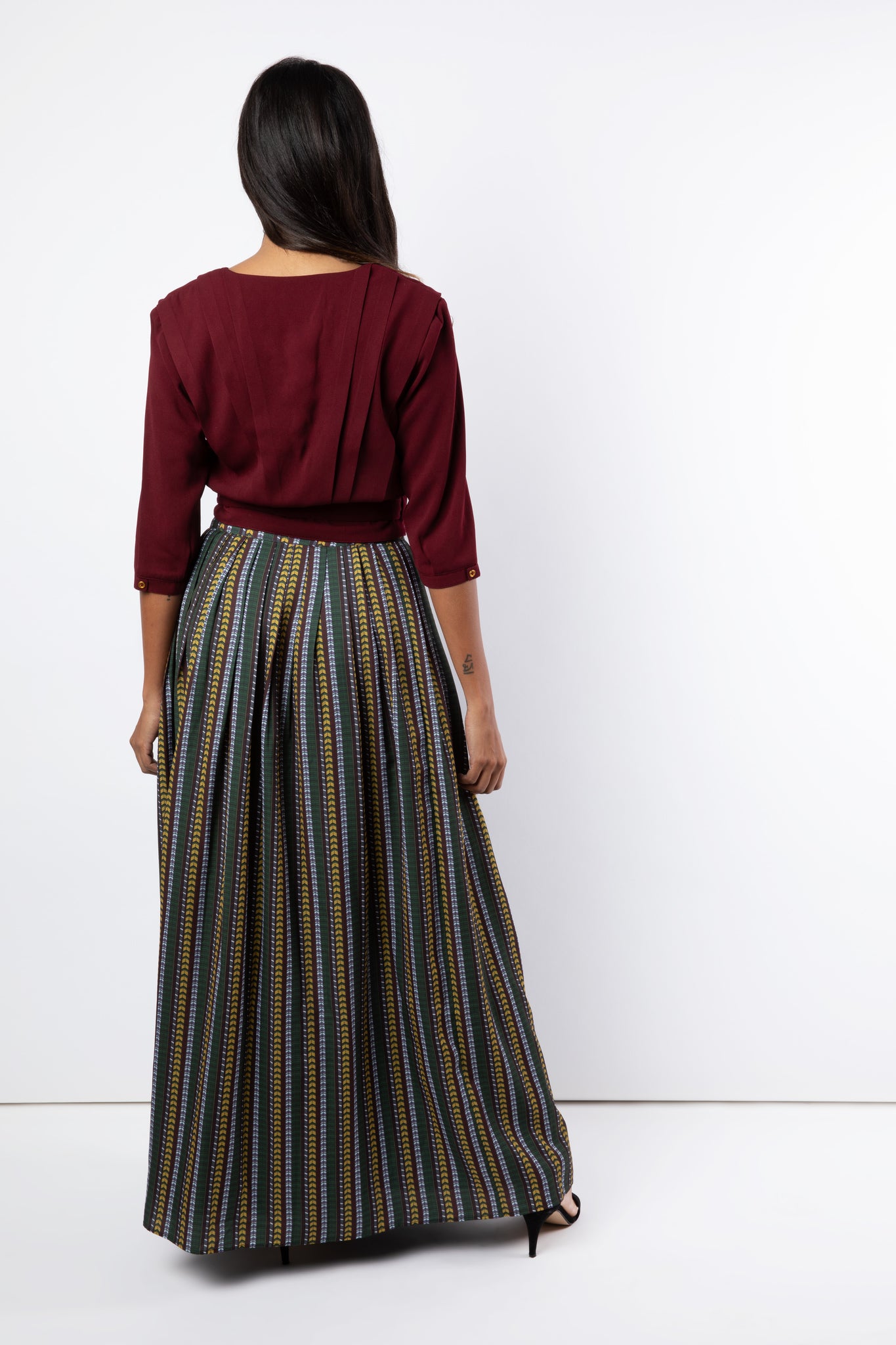 Back view of pleated maroon shirt with printed maxi skirt