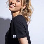 Model wears a black organic cotton boxy fit cropped t-shirt with logo patch on sleeve