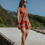 Woman in a colorful dress standing on wooden steps with a scenic background