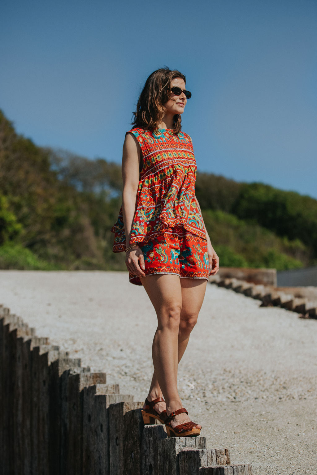 Woman in a colorful dress standing on wooden steps with a scenic background