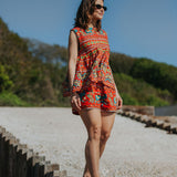 Woman in a colorful dress standing on wooden steps with a scenic background