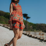 Woman in a colorful dress standing on a path with a clear blue sky and greenery in the background