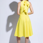 Back view of yellow racer back dress with flared skirt and bow detail