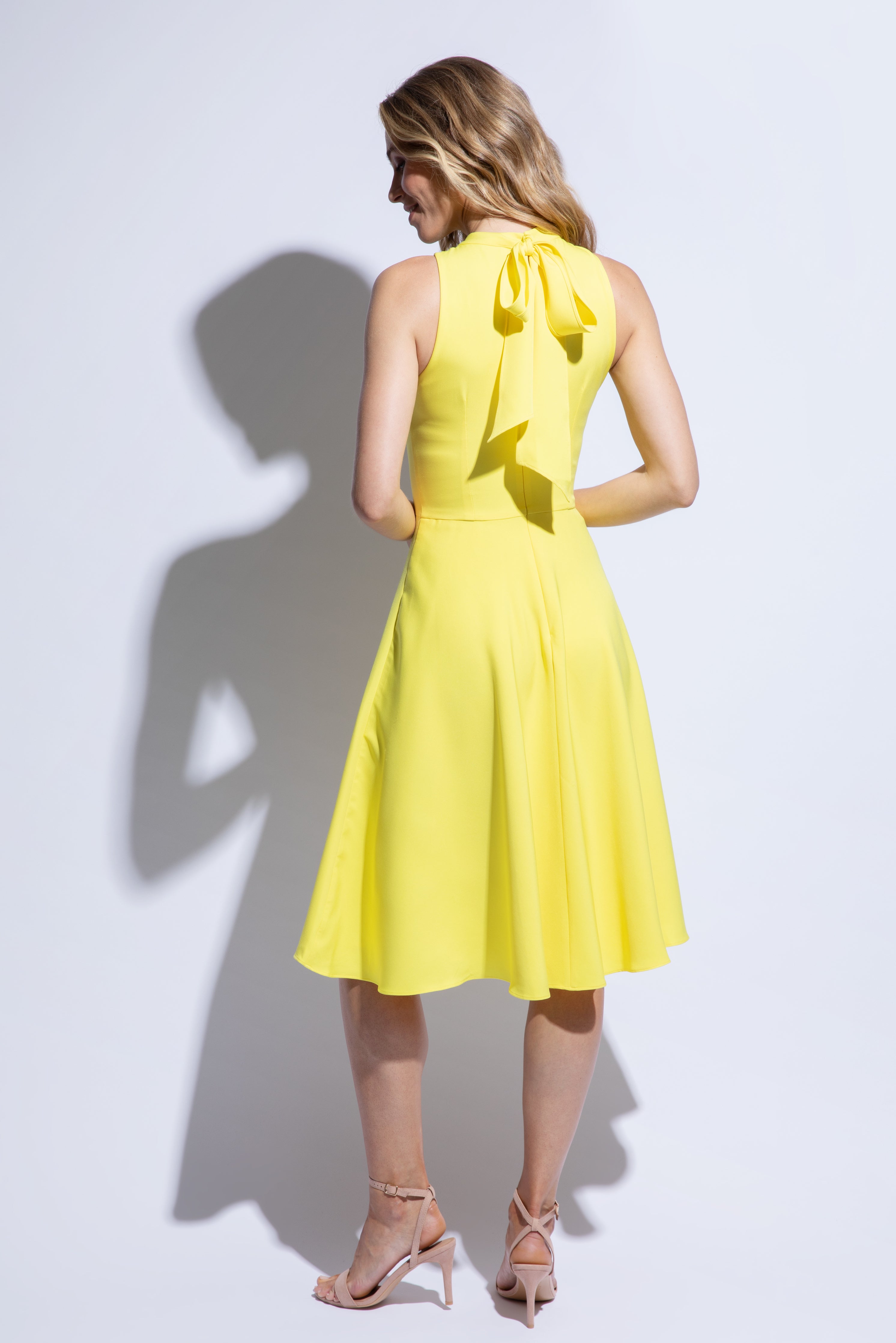Back view of yellow racer back dress with flared skirt and bow detail