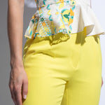 Close up of bright yellow trouser pocket detail and embroidered top peplum 