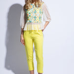 Model wears colourful tulle embroidered top with fitted yellow trousers