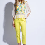 Model wears embroidered sheer top with sleeves and yellow tailored cropped trouser