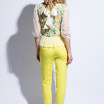 Back view of sheer embroidered and colourful top with fitted yellow trouser and bow detail