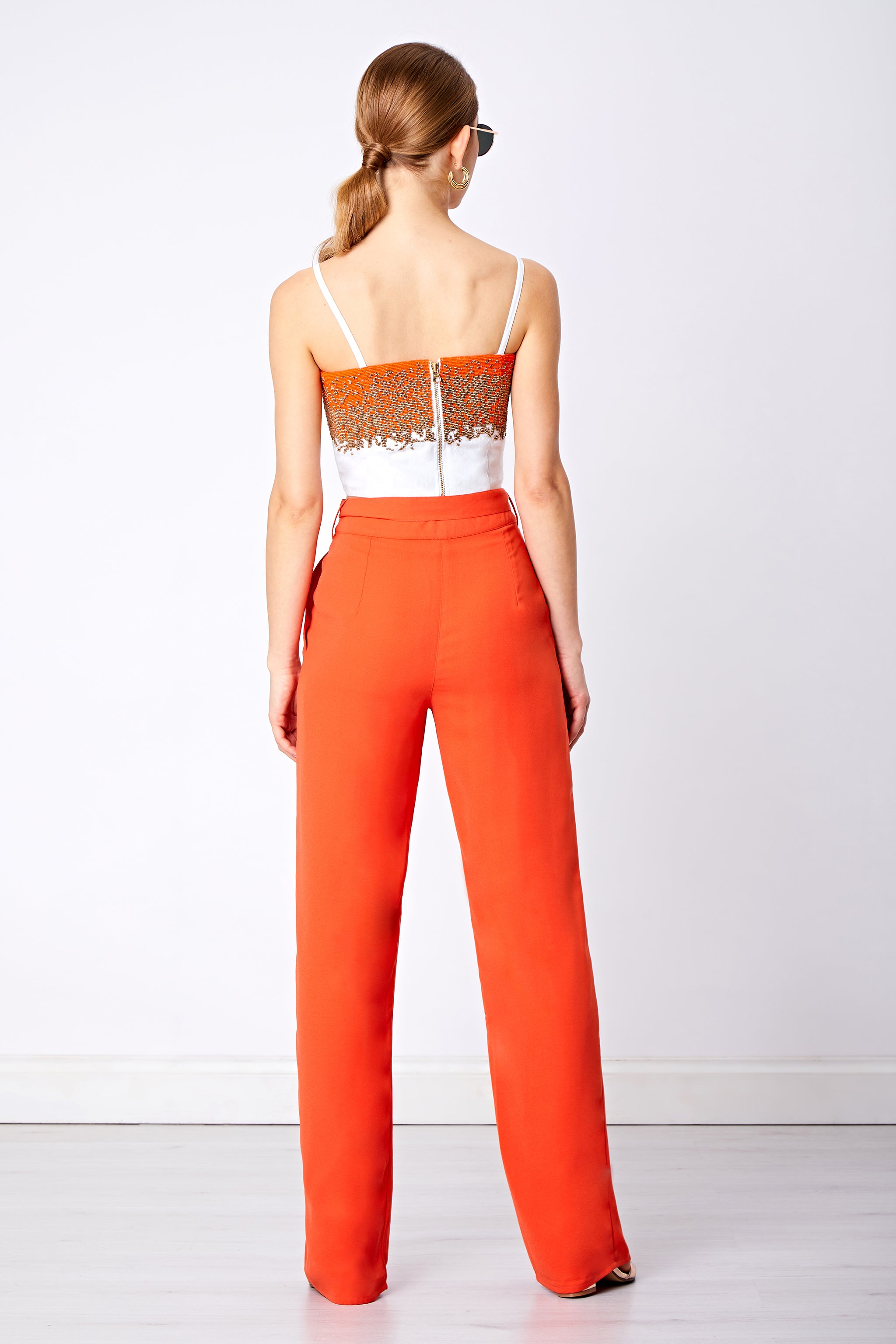 Back view of orange wide leg trouser and beaded bralette with zip detail