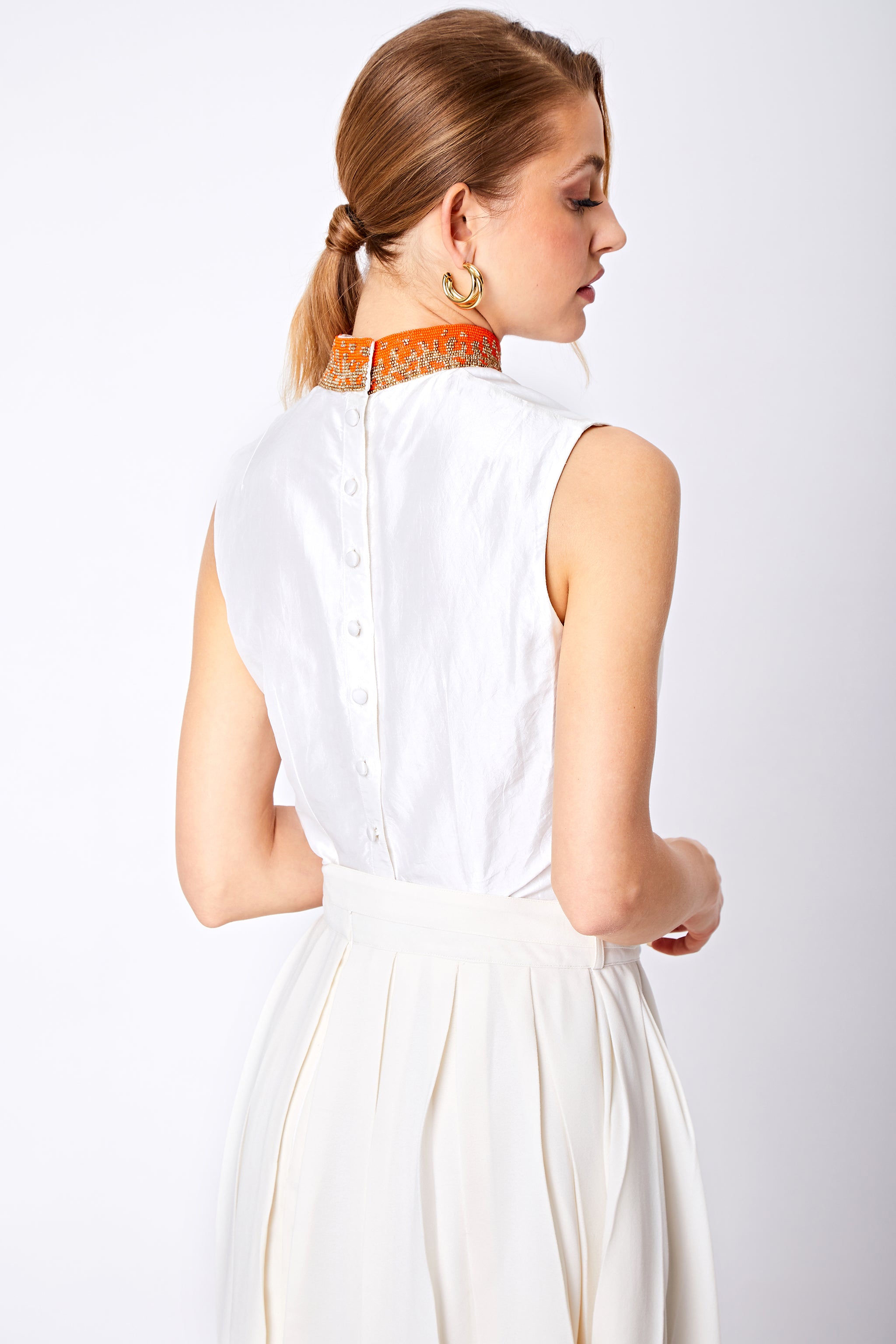 Back view close up of beaded top and white box pleat skirt