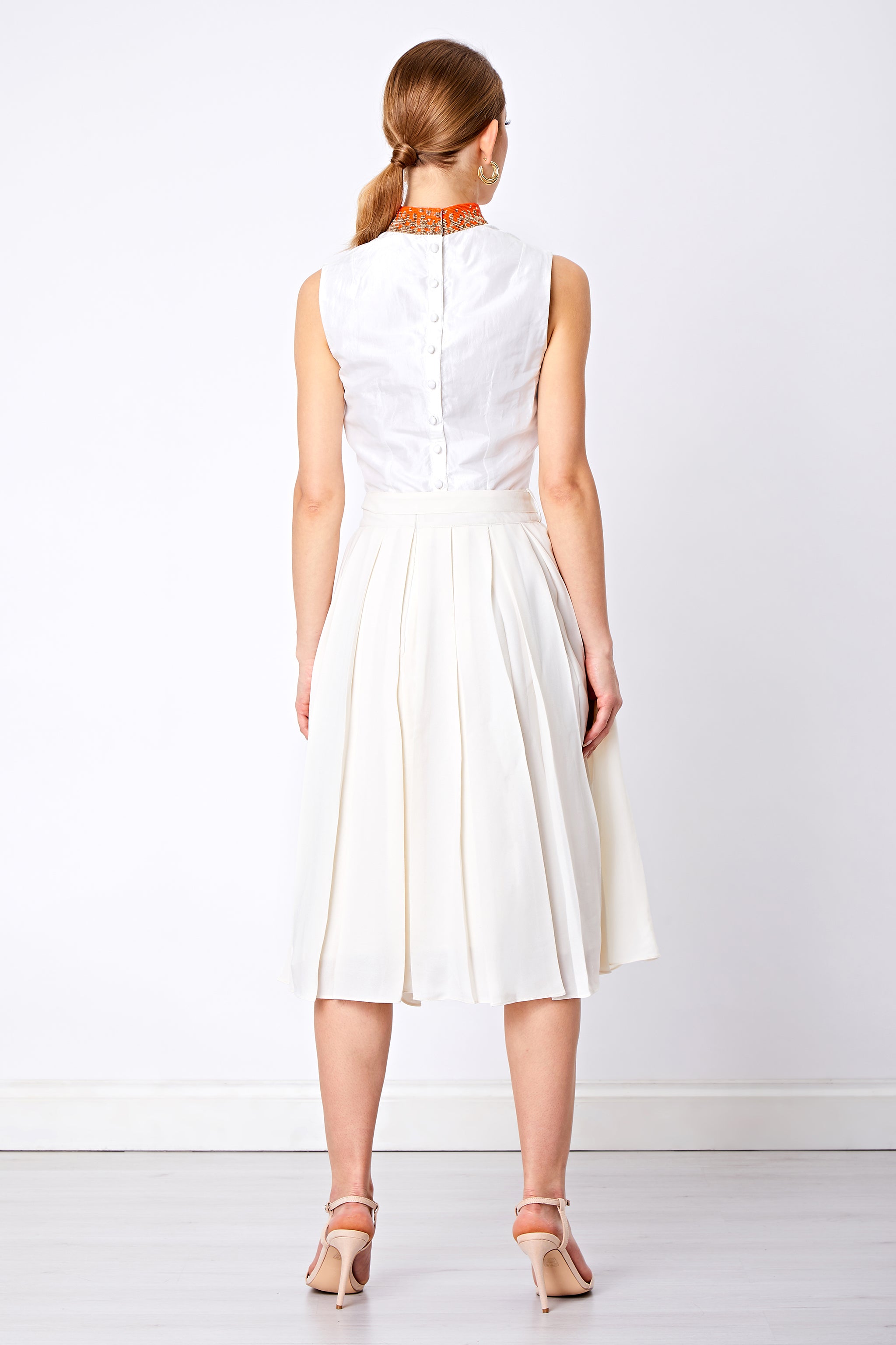 Back view of beaded silk top and white pleated flared skirt