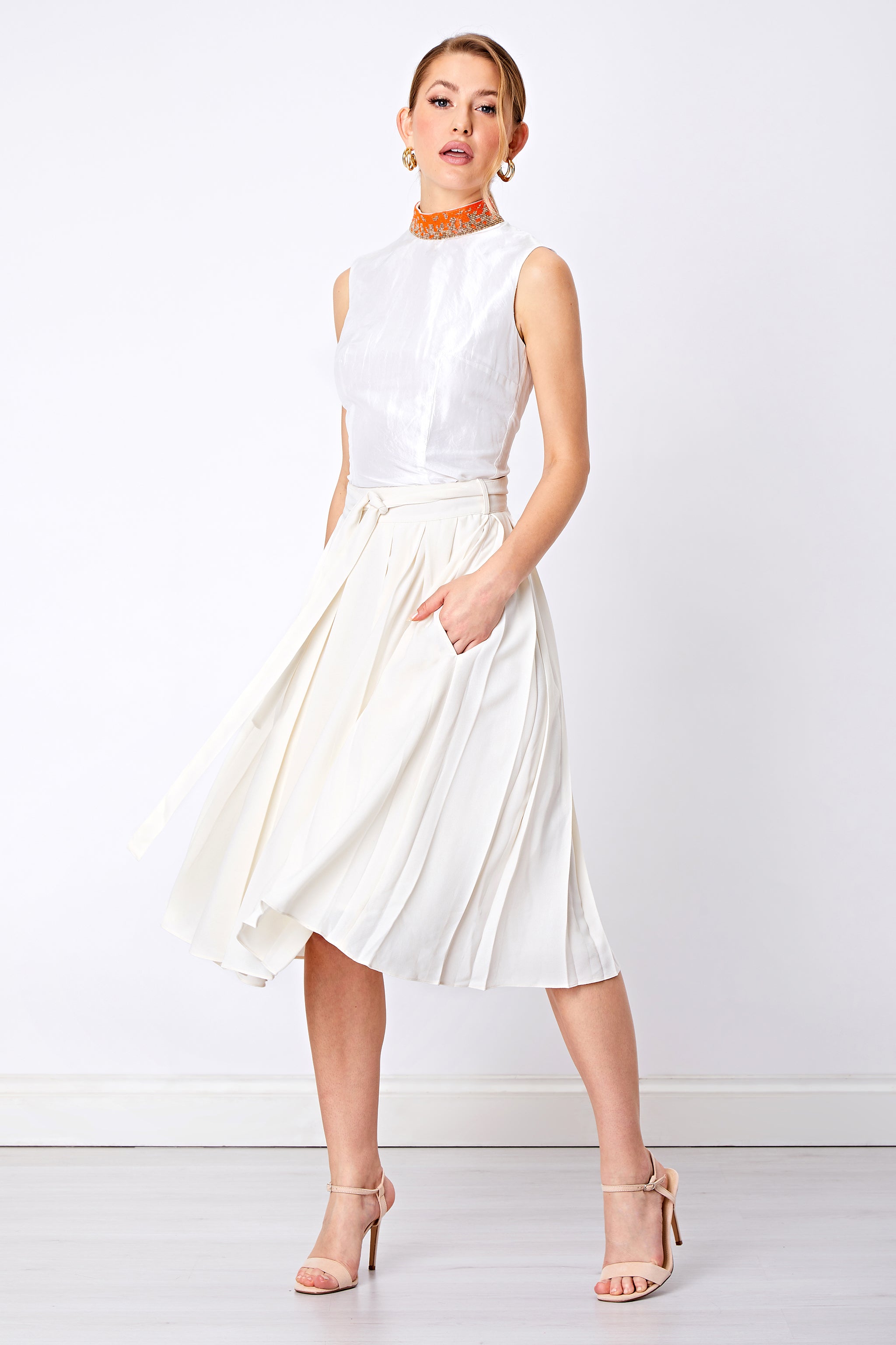 Model wear flared white pleated skirt with sleeveless top