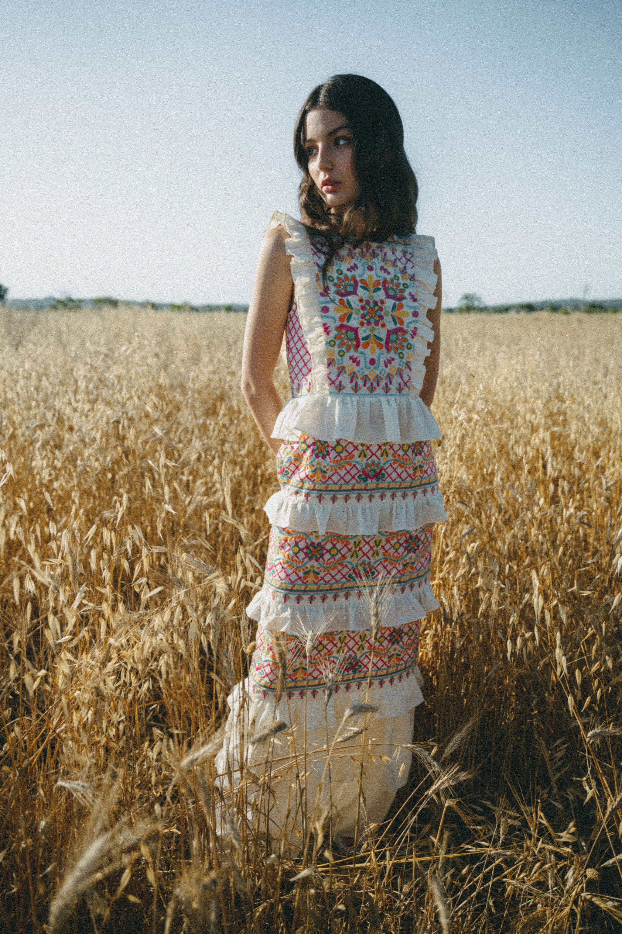 girl in field wearing embroidered colourful maxi dress