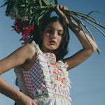 girl with flowers wearing colourful embroidered top with frills