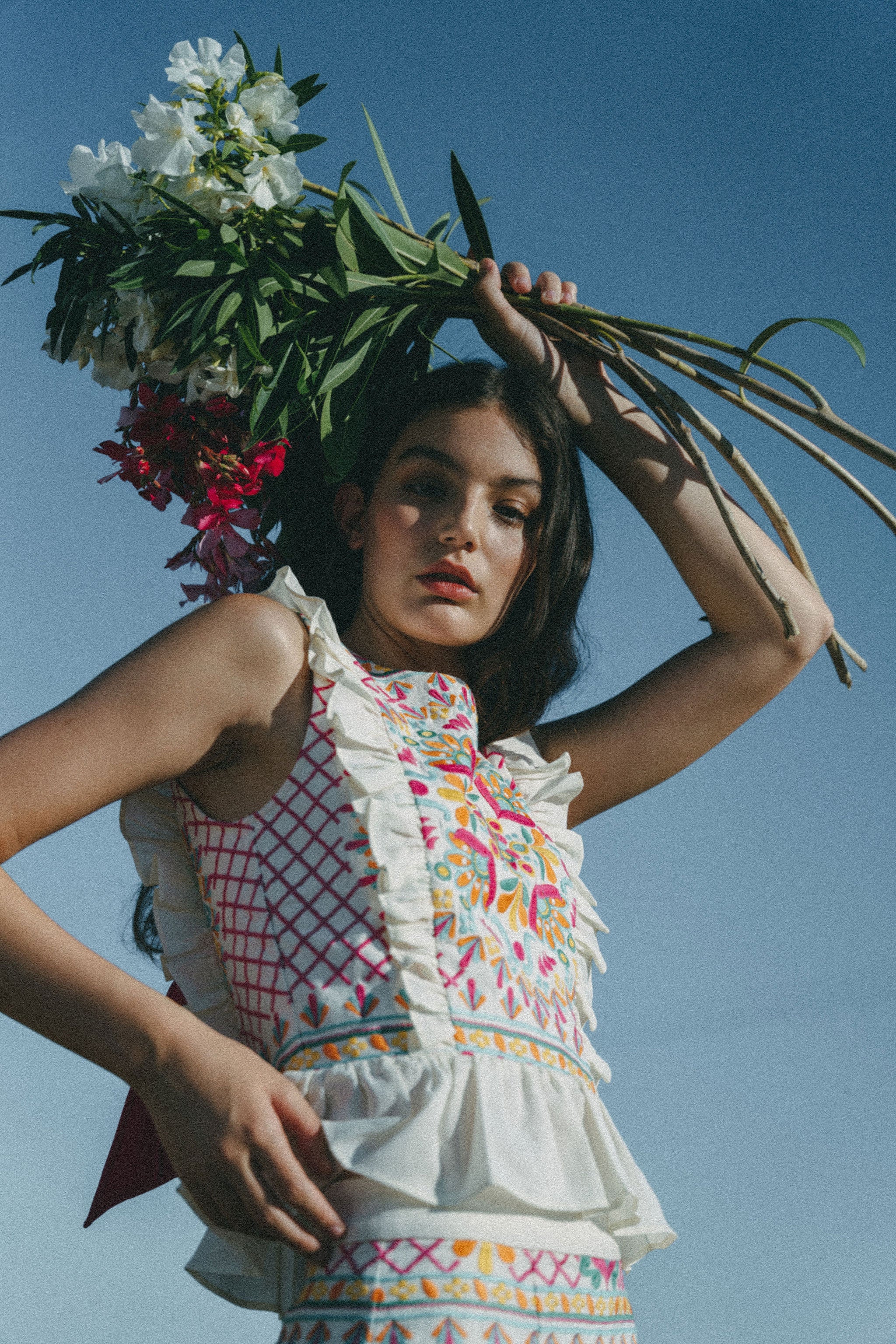 girl with flowers wearing colourful embroidered top with frills