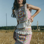 girl in field wearing colourful embroidered top and skirt with frills