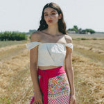 girl in field with white crop top and embroidered colourful sarong