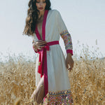 girl in field with white embroidered cover up with pink border