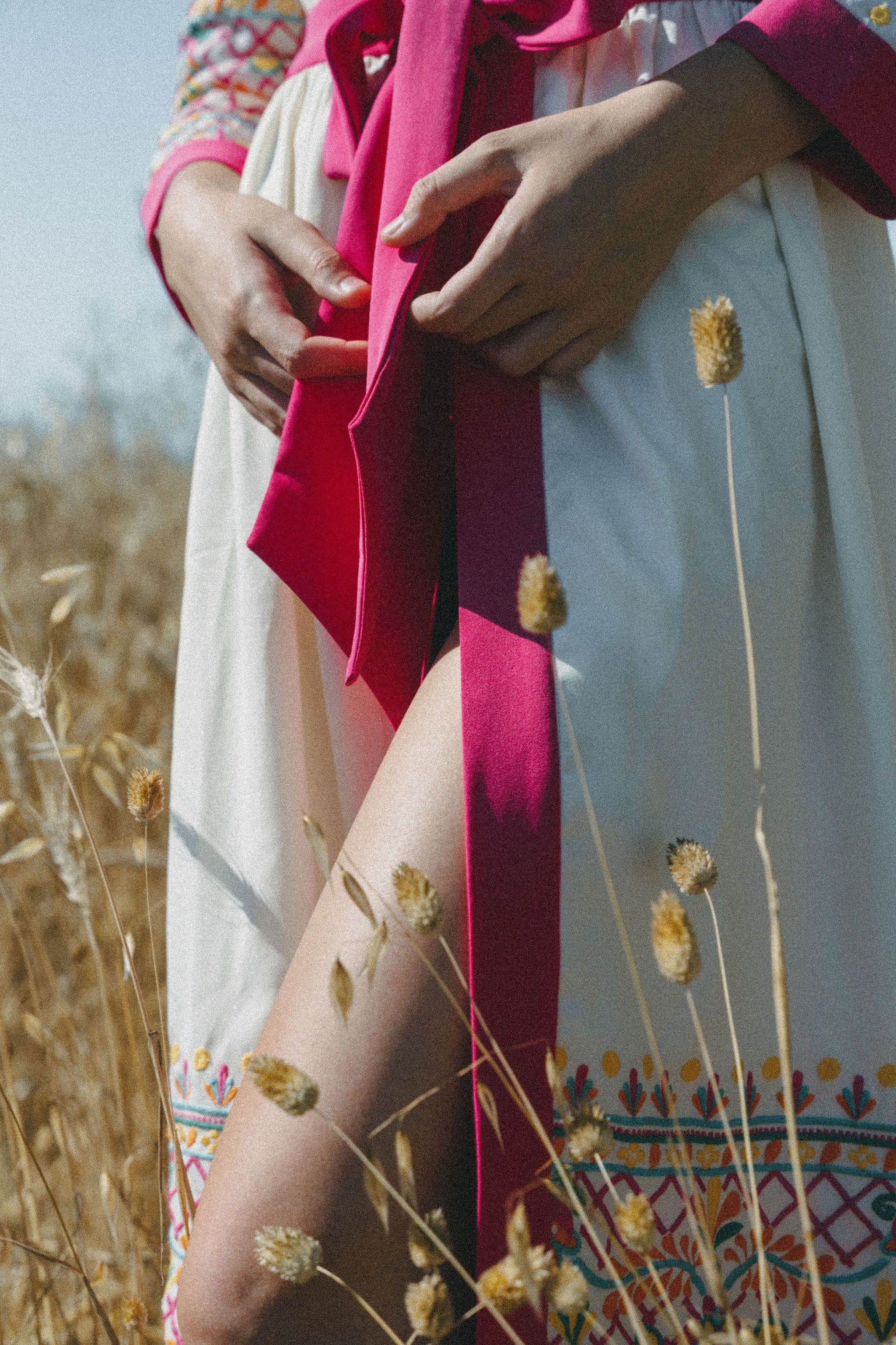 close up of embroidered coverup with pink border and belt