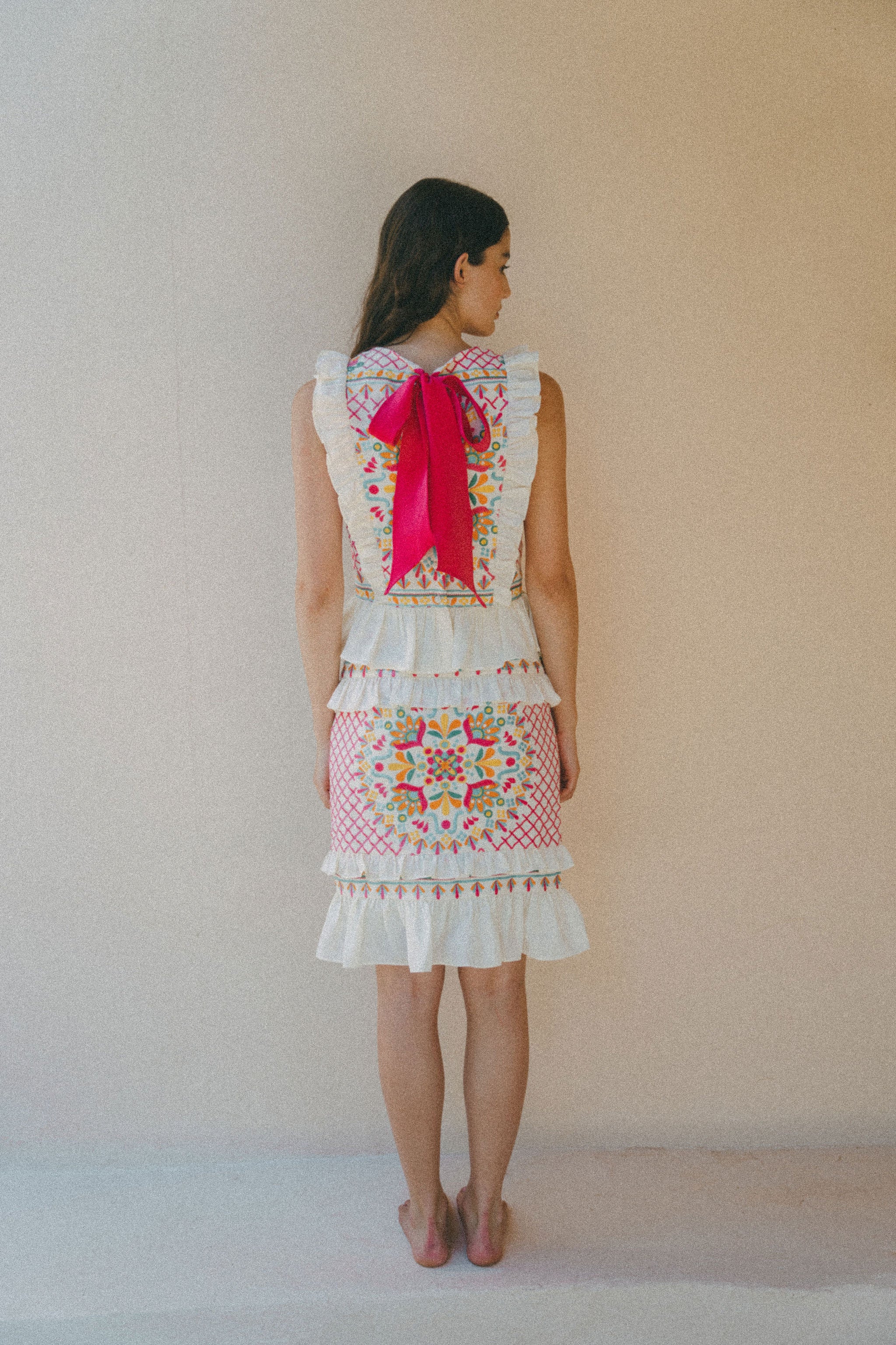 back of colourful embroidered top with pink bow and skirt