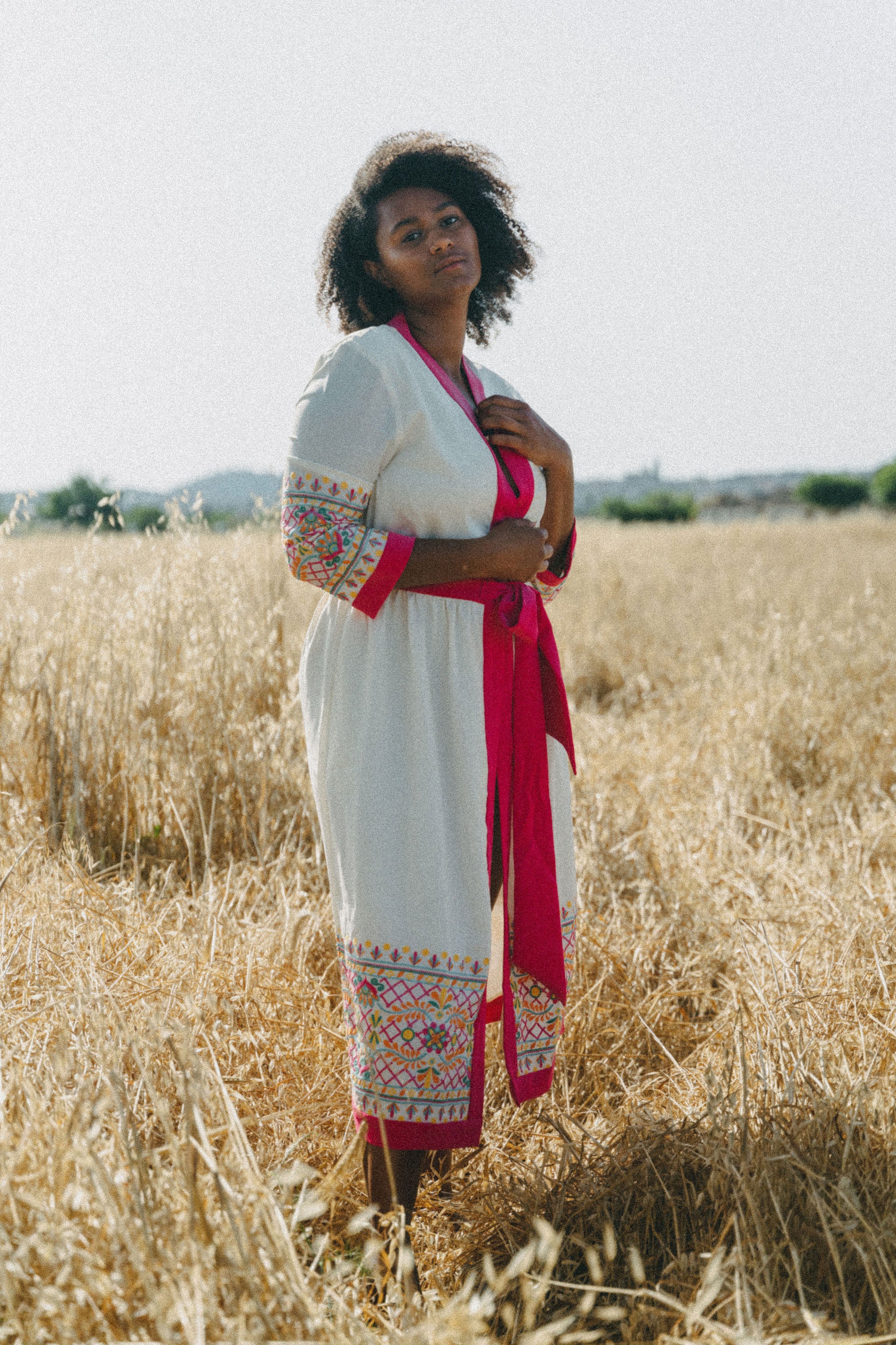 cream cover up with colourful embroidery and pink border and belt.