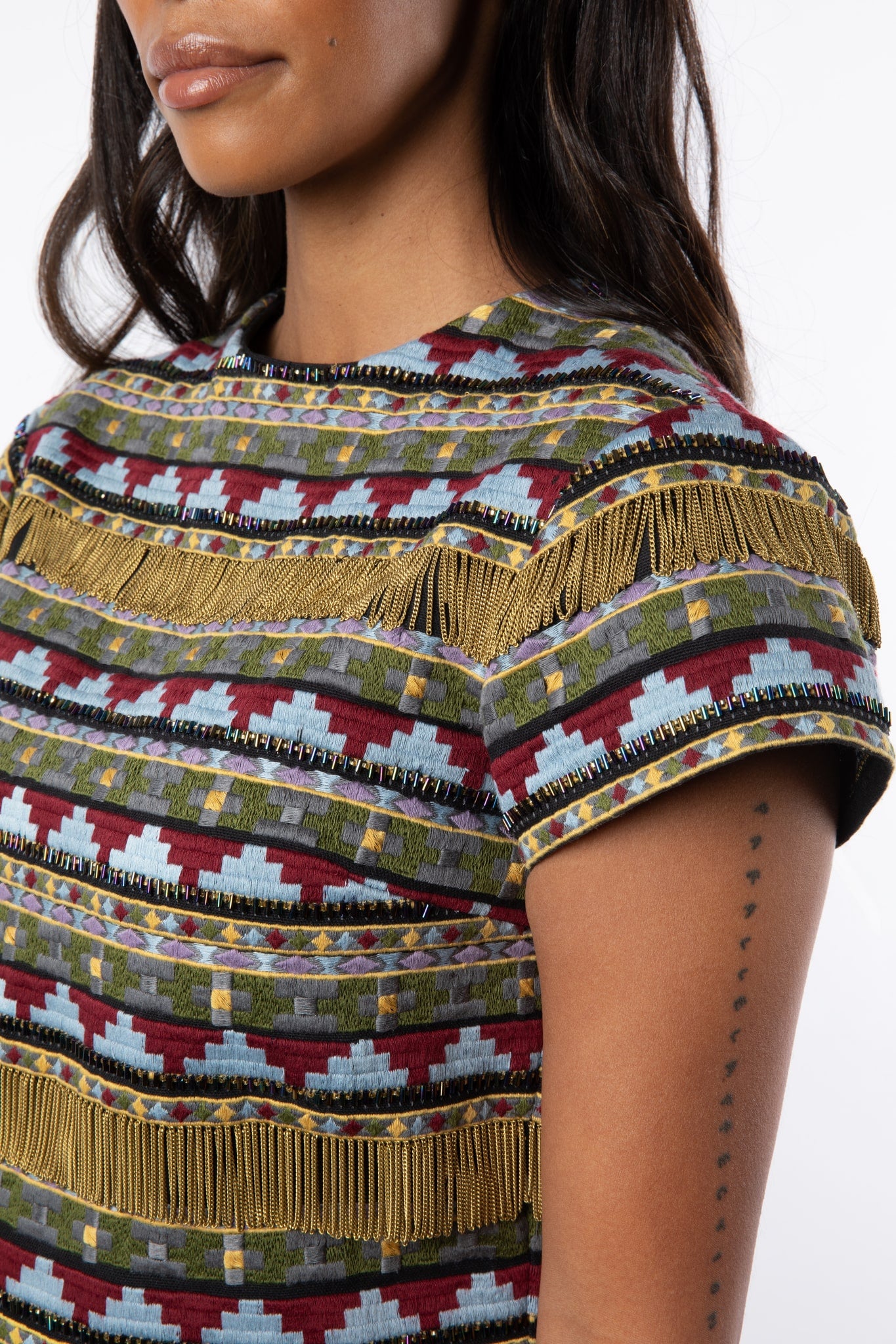 Close up view of cotton short sleeve embroidered top with embroidery, beads and chain fringe
