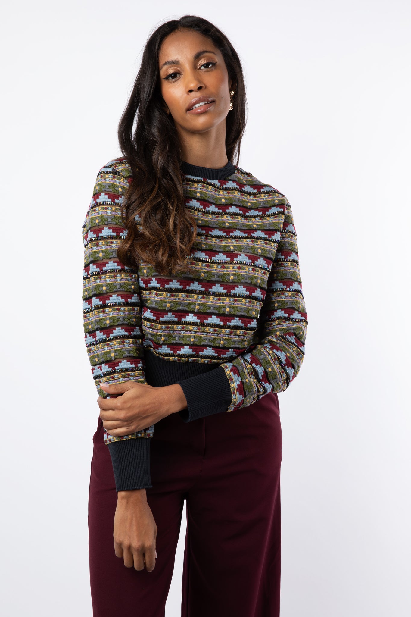 Model wears embellished sheer jumper with maroon trouser