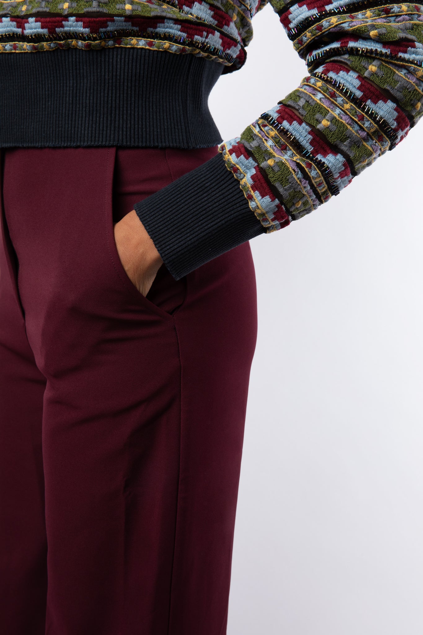 Close up of embellished jumper details and maroon trouser pocket
