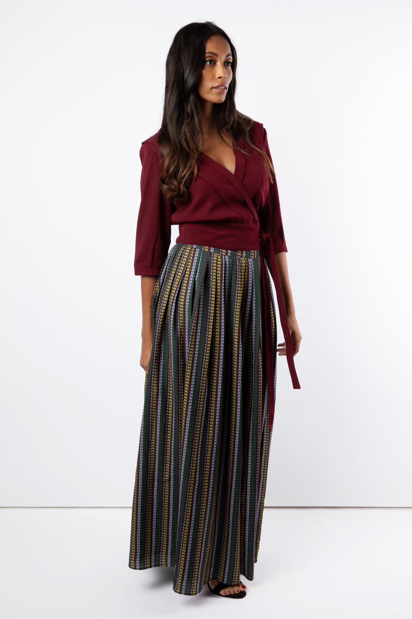 Model wears pleated and printed maxi skirt with maroon shirt