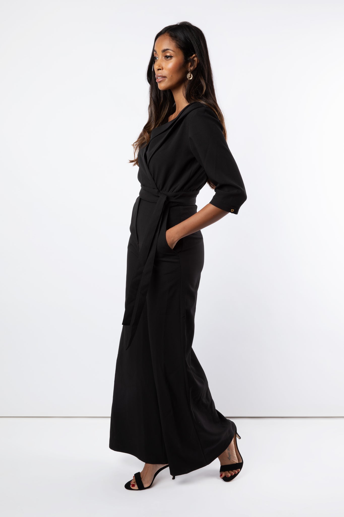 Model wears black jumpsuit with wide leg trouser