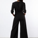 Back detail of jumpsuit wit hands in pockets and wide leg trouser
