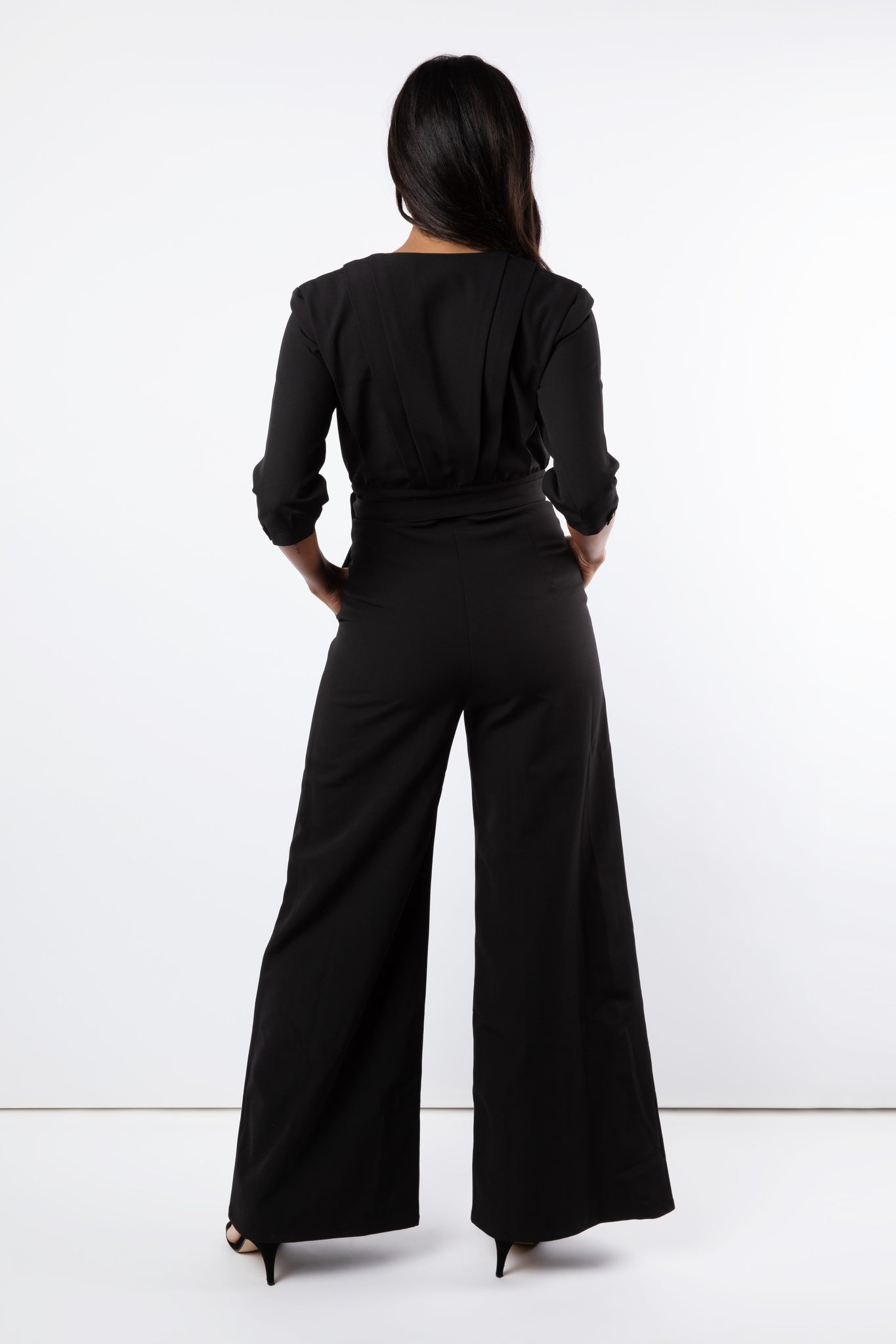 Back detail of jumpsuit wit hands in pockets and wide leg trouser
