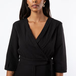 Close up of model wearing black jumpsuit with pleat detail