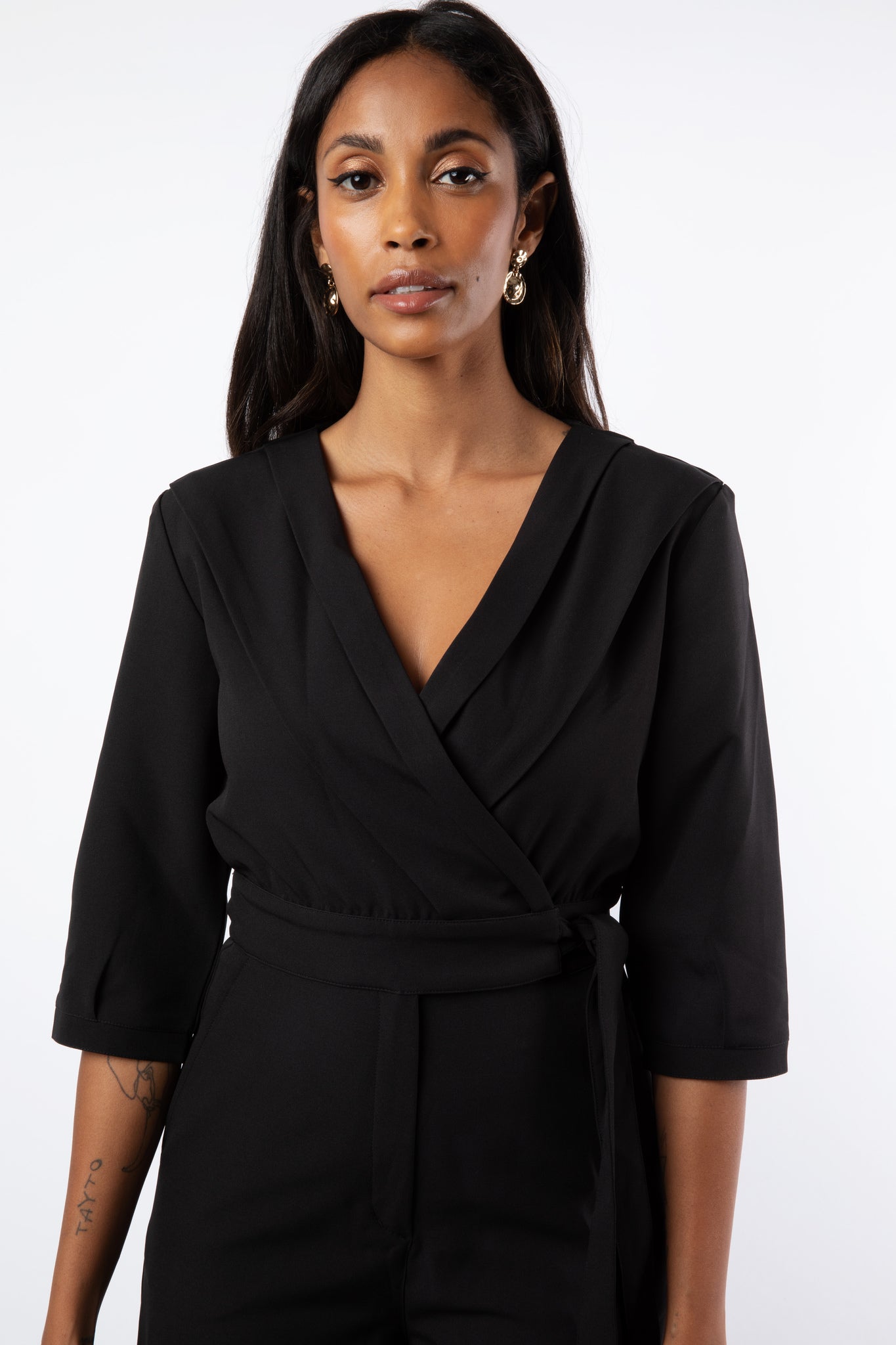Close up of model wearing black jumpsuit with pleat detail